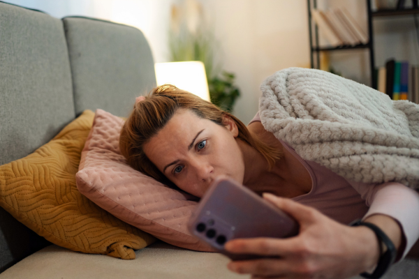 A pregnant woman in bed googling labor symptoms on her phone.